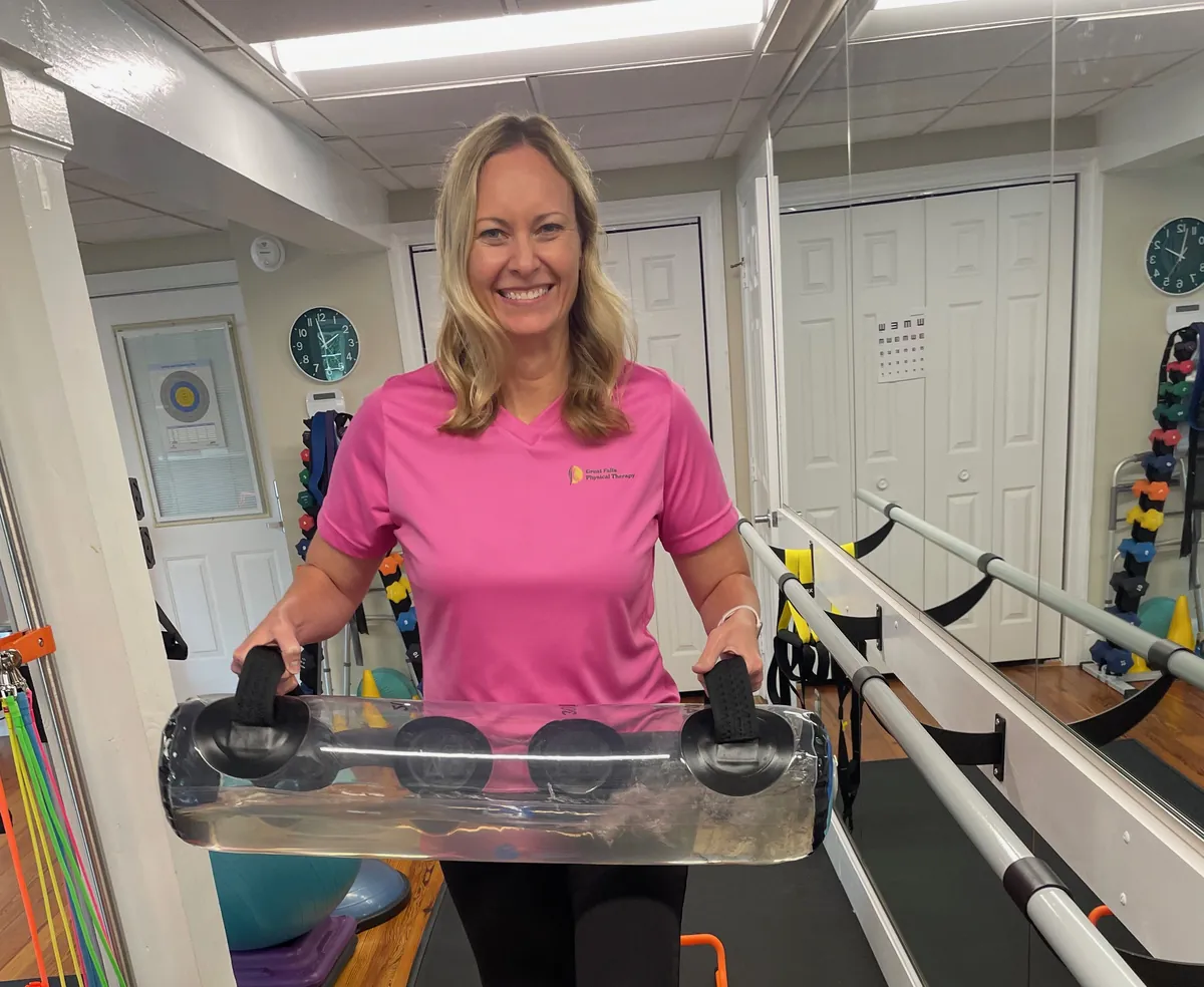 Physical therapist demonstrating balance and coordination training with a weighted water bag