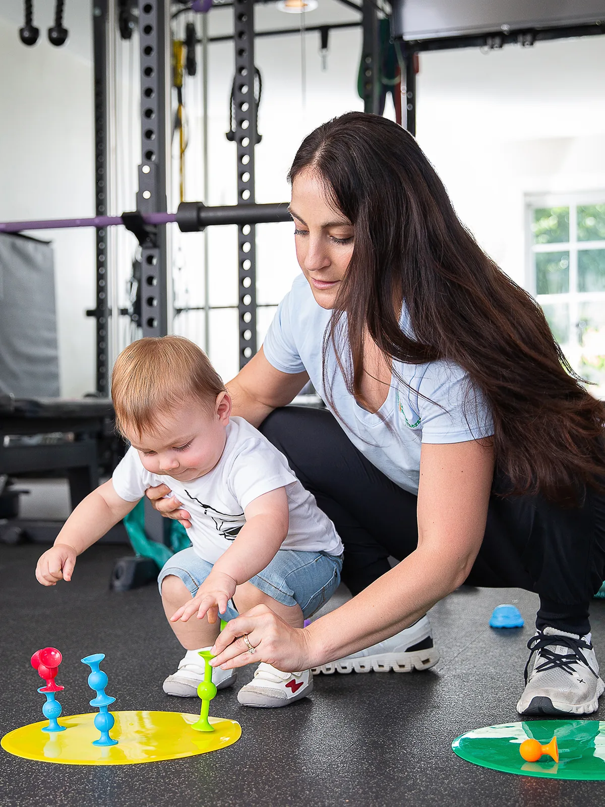 Pediatric physical therapist playing with a toddler during a movement and coordination session